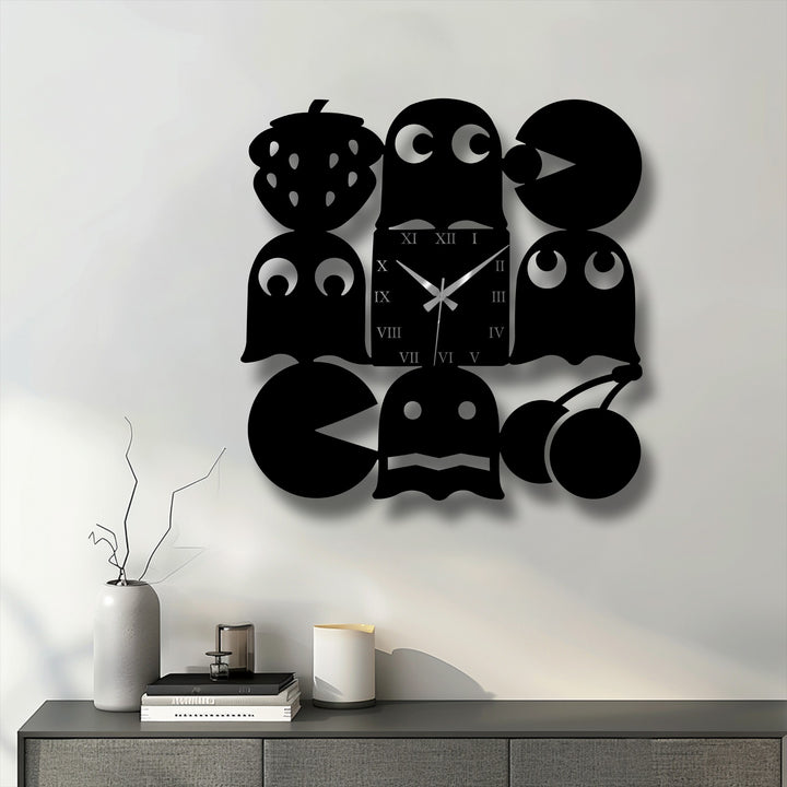 A gray vase with branches, stacked books, and a white candle are on a cabinet below the playful metal wall decor.