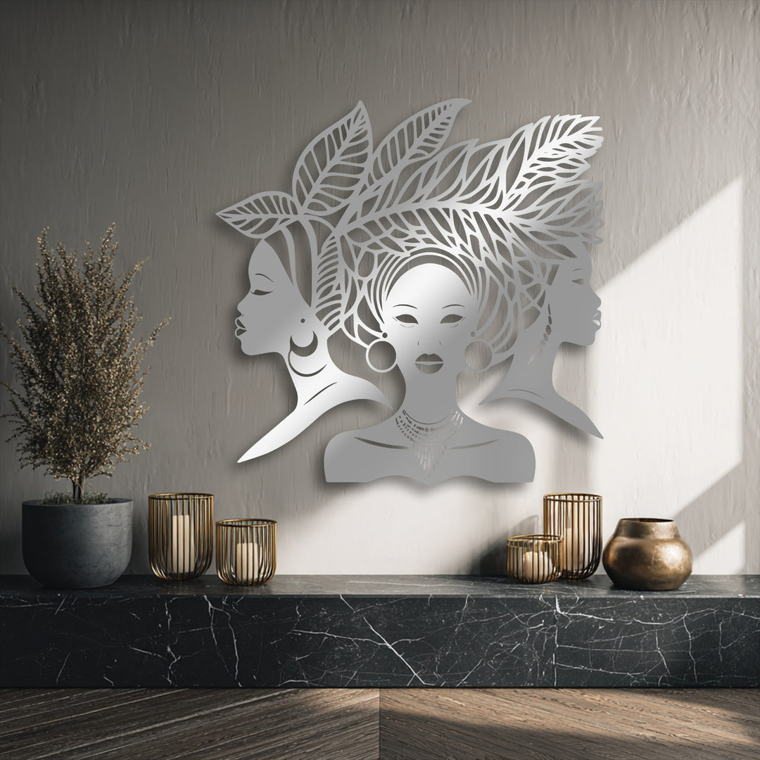 The visual rhythm of this decorative metal art piece showcases elegant African women silhouettes, their leafy hair creating a harmonious flow against the textured wall.