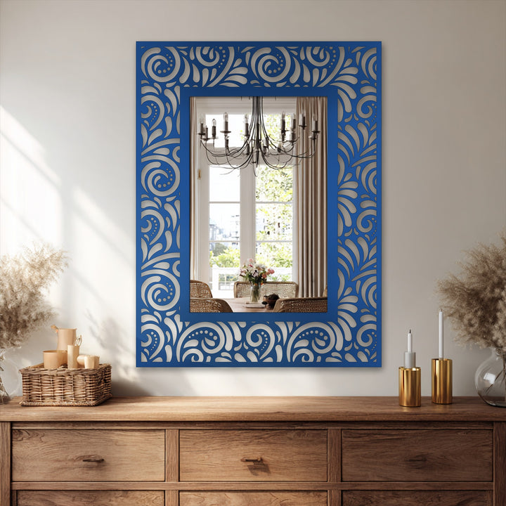Neutral color temperatures highlight the ornate floral scroll pattern on this mirror for wall decor, enhanced by the reflection's chandelier and warm wood tones.