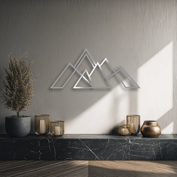 The serene mood of this minimalist setting is enhanced by the unique metal wall art depicting geometric mountains, casting soft shadows.