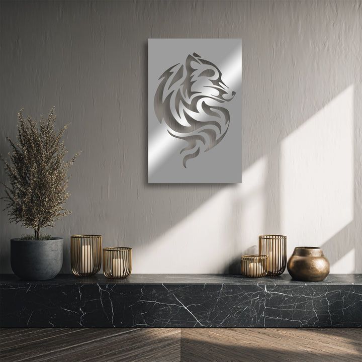 Dramatic sunlight and sharp shadows accentuate the shimmering tribal wolf metal artwork, emphasizing its abstract design on a textured gray wall.
