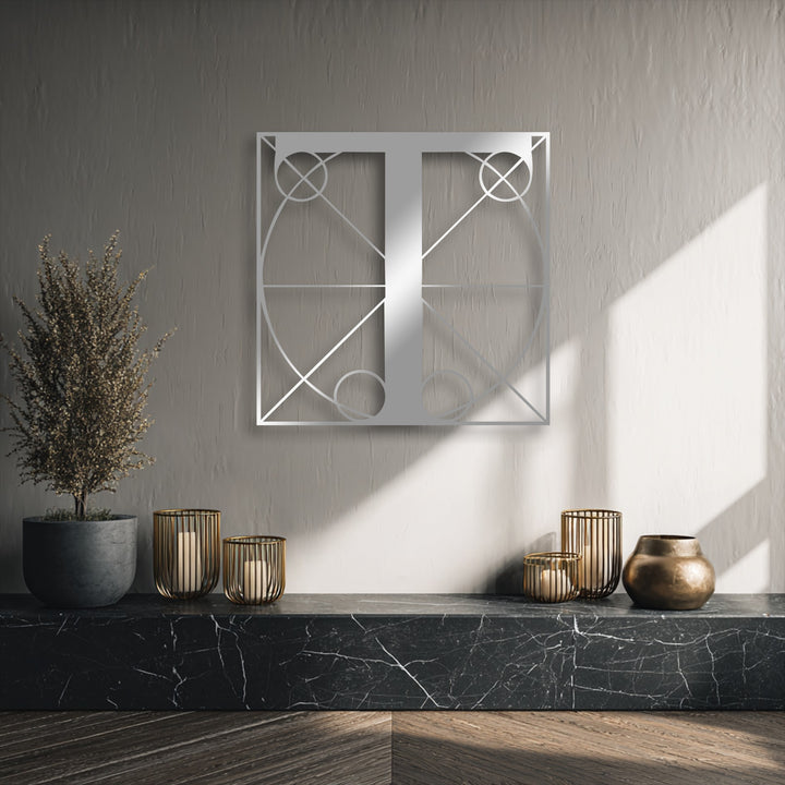 The textured gray background wall, softly lit by sunlight and featuring a crisp shadow, enhances the modern geometric letter T metal decoration wall art.