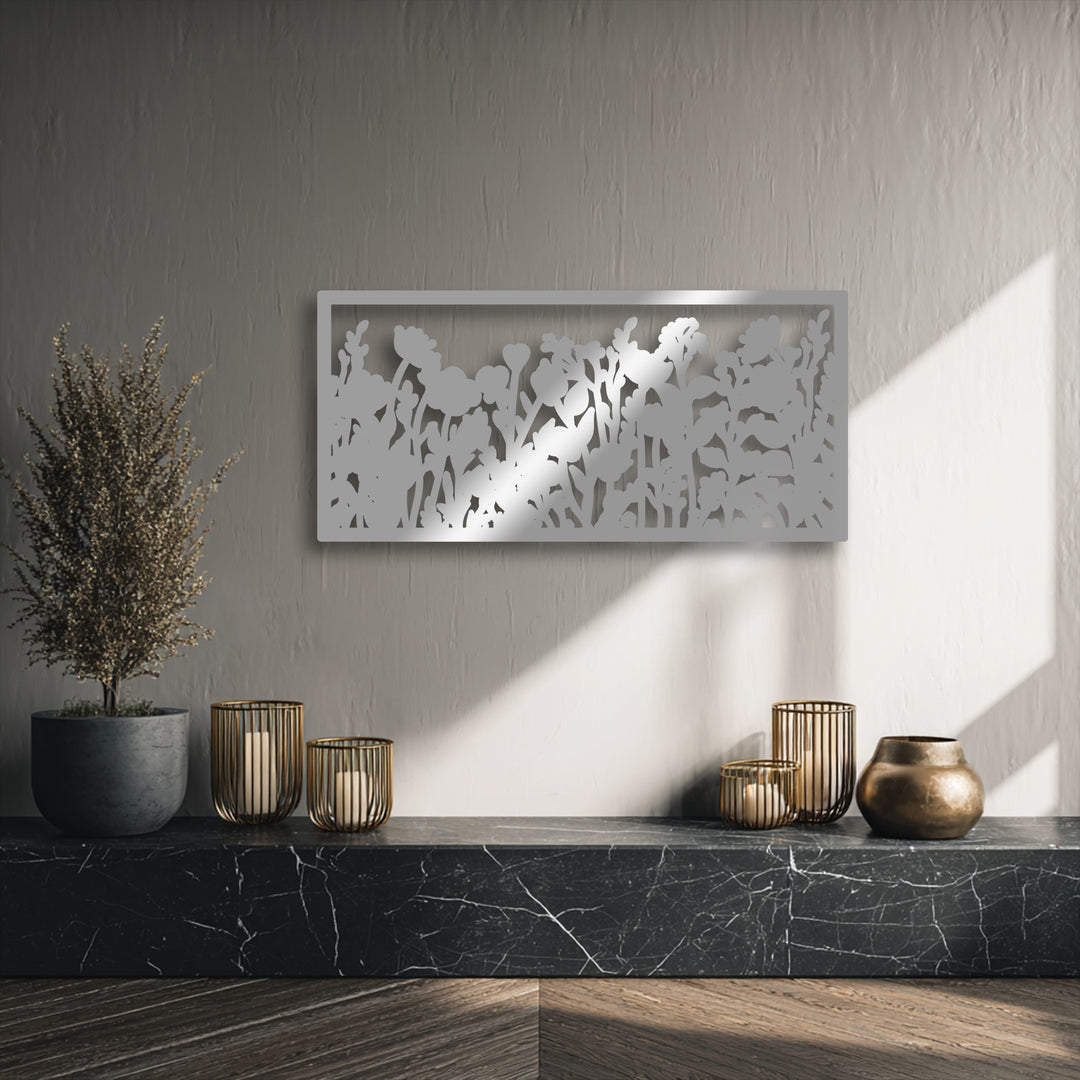 The muted color temperature of the wall is warmed by bright sun streaks, emphasizing the elegant wildflower silhouette metal artwork.