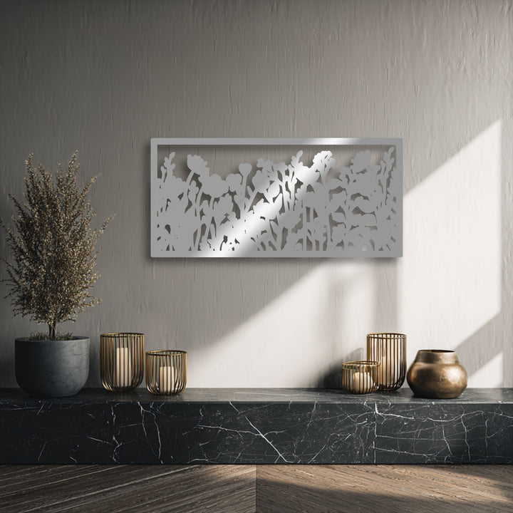 The muted color temperature of the wall is warmed by bright sun streaks, emphasizing the elegant wildflower silhouette metal artwork.