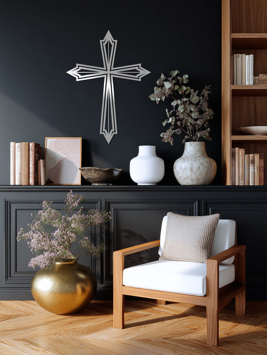 Dark interior scene featuring layered silver cross decoration wall art against a charcoal wall above a mantelpiece with vases, books, and a wooden chair.
