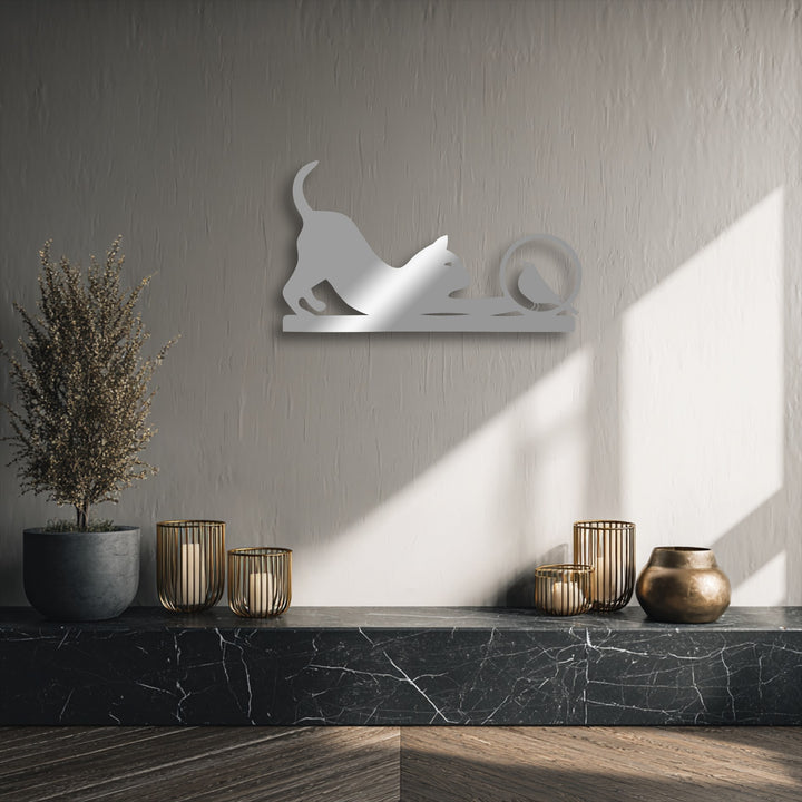 The unique metal wall art of a playful cat and bird is smooth and reflective against the subtly textured wall and veined marble.