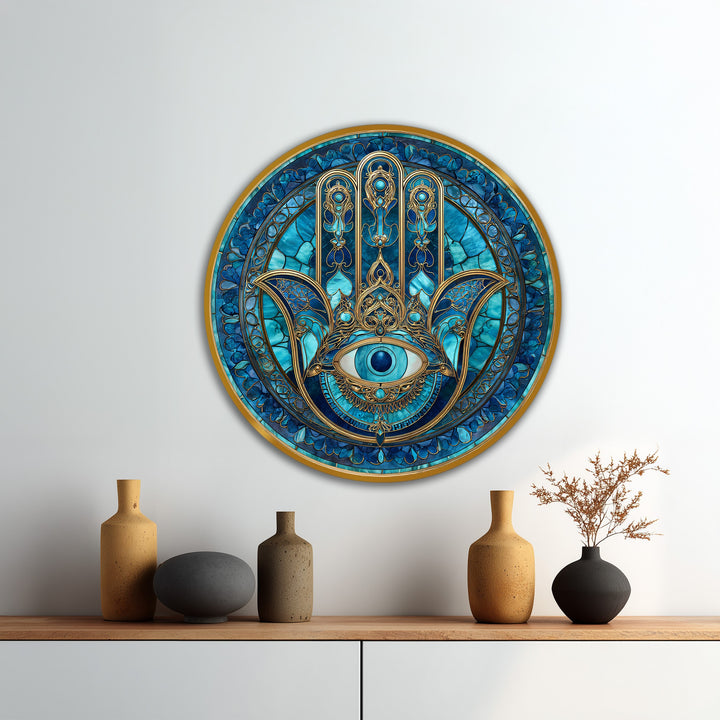 Exhibiting rich color saturation, the blue Nazar Hamsa protective eye round oil painting decoration on wood features gold detailing in a striking presentation.