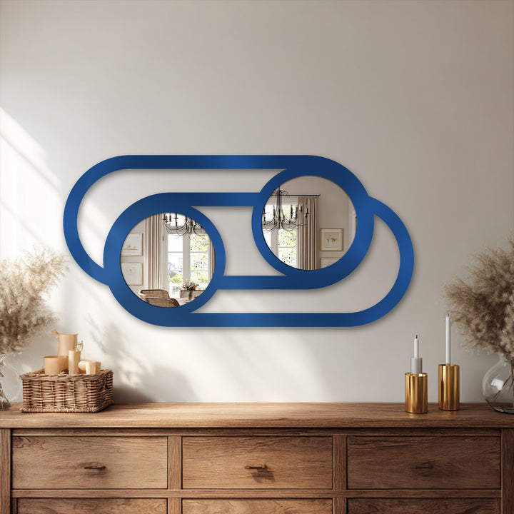 Subtle shadows add depth to the neutral background, highlighting the minimalist, linked-circle design of the blue metal artwork decorative mirror.