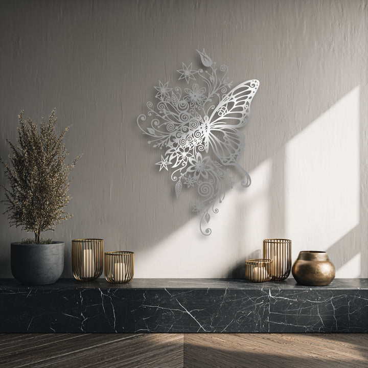 The ornate silver floral butterfly metal art for wall is the focal point, casting delicate shadows on the textured wall illuminated by sunlight.