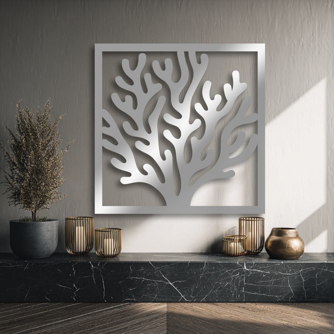 The muted color saturation of this elegant Coral Frame decorative metal art piece highlights its sleek silver design against a textured gray wall.