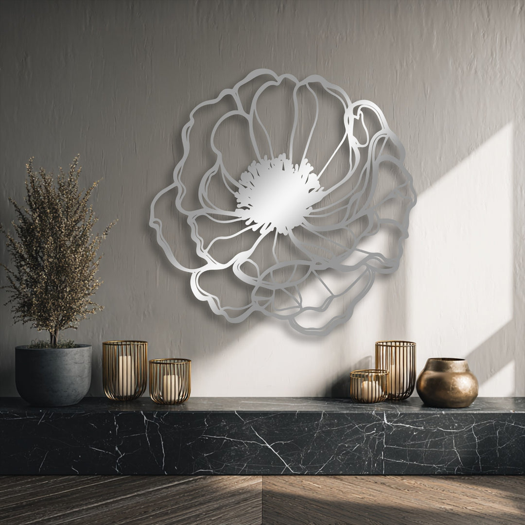 Muted gray tones highlight the minimalist floral metal artwork, elegantly presented against a light-textured wall with dappled sunlight.