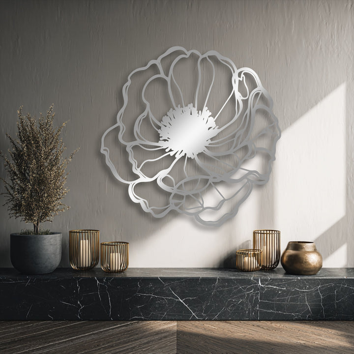 Muted gray tones highlight the minimalist floral metal artwork, elegantly presented against a light-textured wall with dappled sunlight.