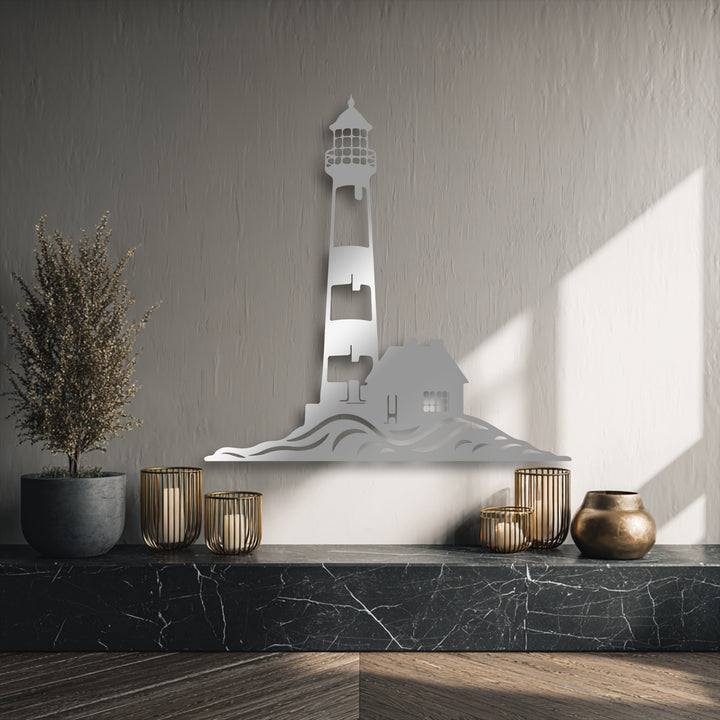 Warm sunlight dramatically illuminates the textured wall, casting distinct shadows that frame the reflective coastal lighthouse silhouette metal artwork.