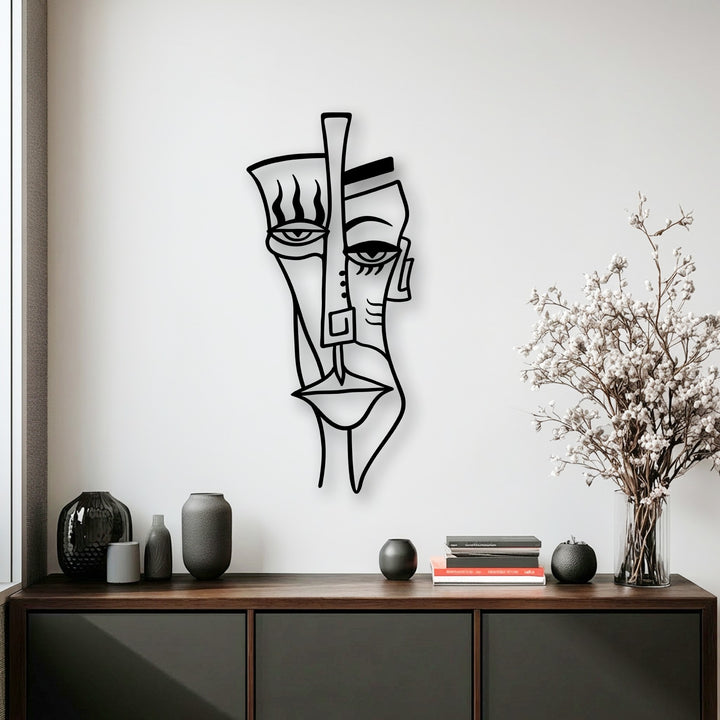 Soft white baby's breath flowers stand in a clear vase, offering a delicate touch to the vibrant abstract tribal face decorative metal art.