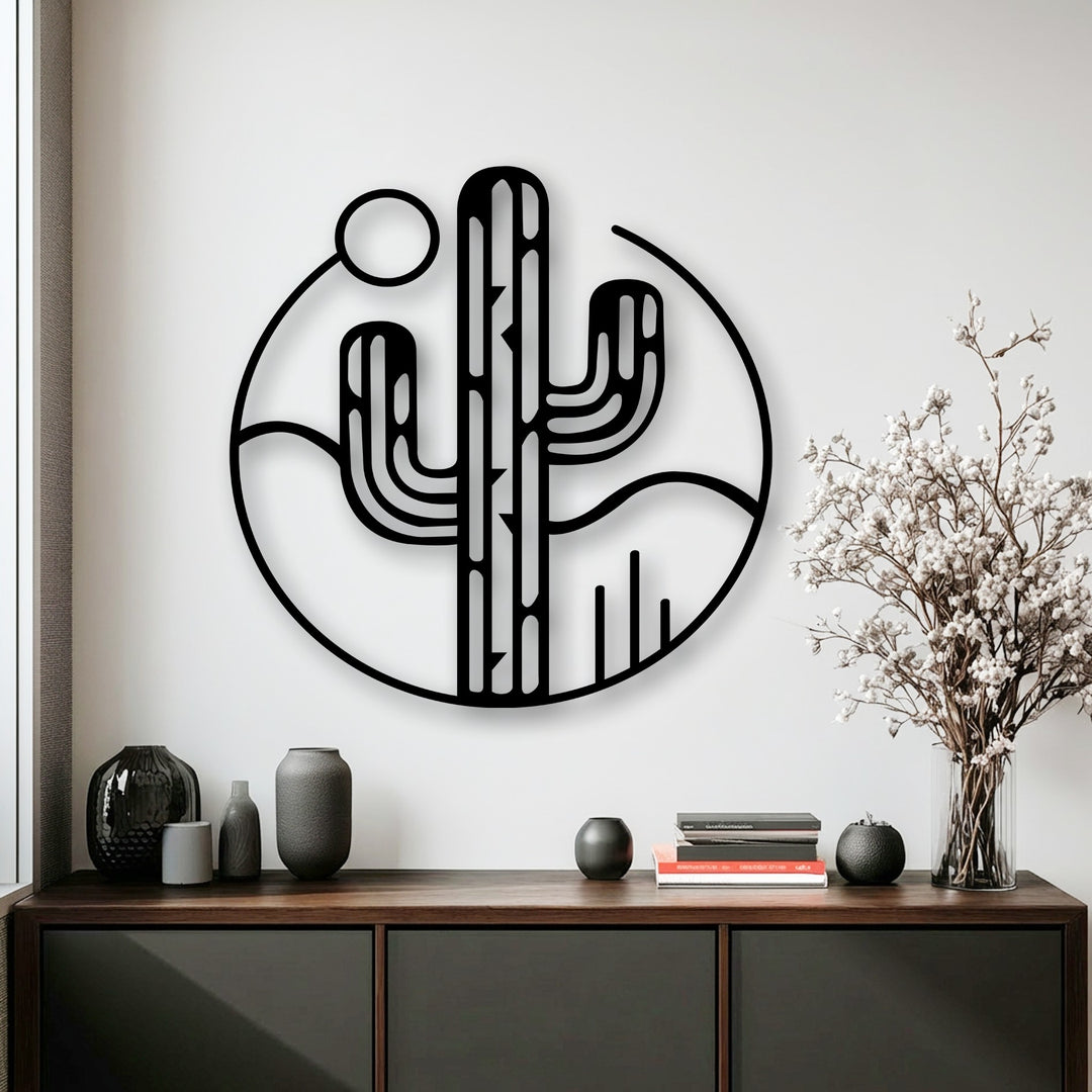 Geometric lines boldly define this black circular metal artwork, showcasing a minimalist desert cactus and landscape design with a simple sun.