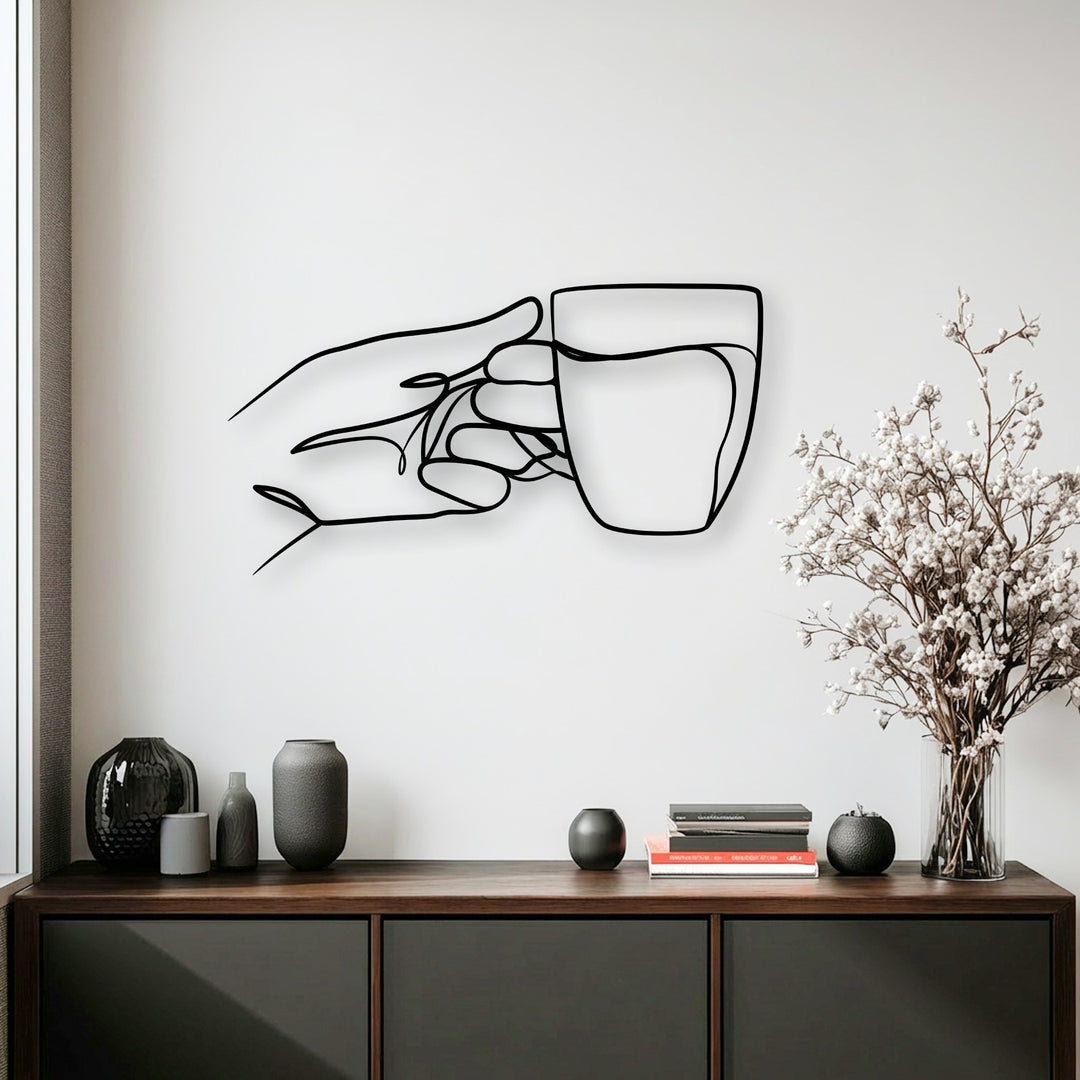 The white background highlights a minimalist hand holding cup decoration wall art, standing above a dark cabinet.
