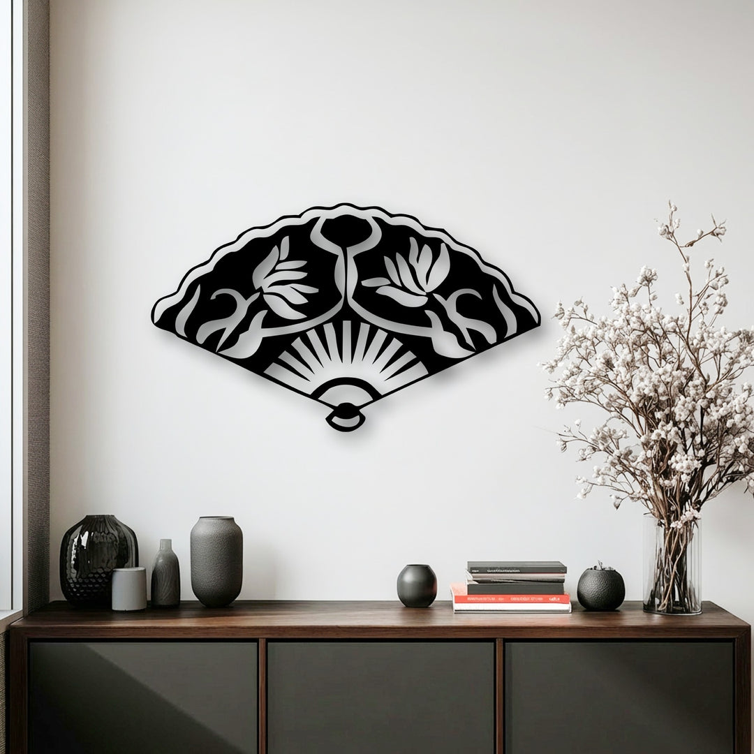 With muted color saturation, a striking black Oriental fan metal wall decor piece featuring floral motifs hangs elegantly above a console table.