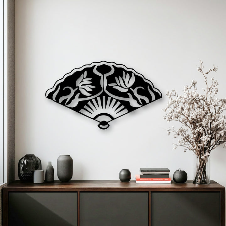With muted color saturation, a striking black Oriental fan metal wall decor piece featuring floral motifs hangs elegantly above a console table.