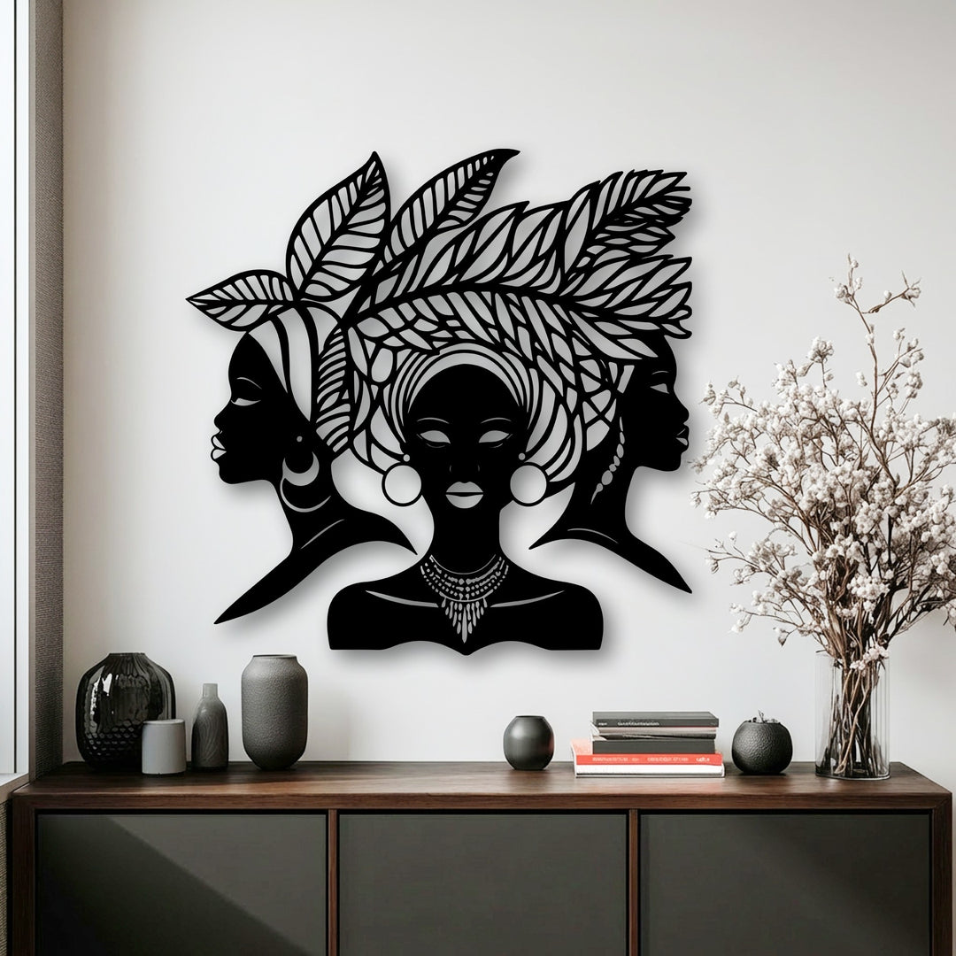 The metal wall decor showcases impressive depth and layers with three African women silhouettes casting subtle shadows against a white wall.
