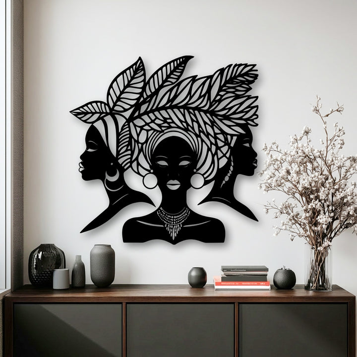 The metal wall decor showcases impressive depth and layers with three African women silhouettes casting subtle shadows against a white wall.