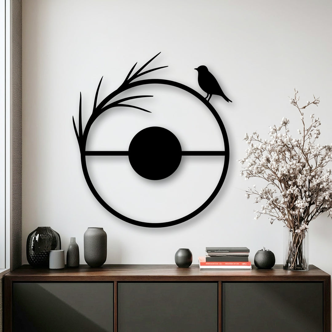 The central subject, a minimalist black circular metal artwork, elegantly depicts a bird perched on a branch silhouette, a stunning metal artwork.