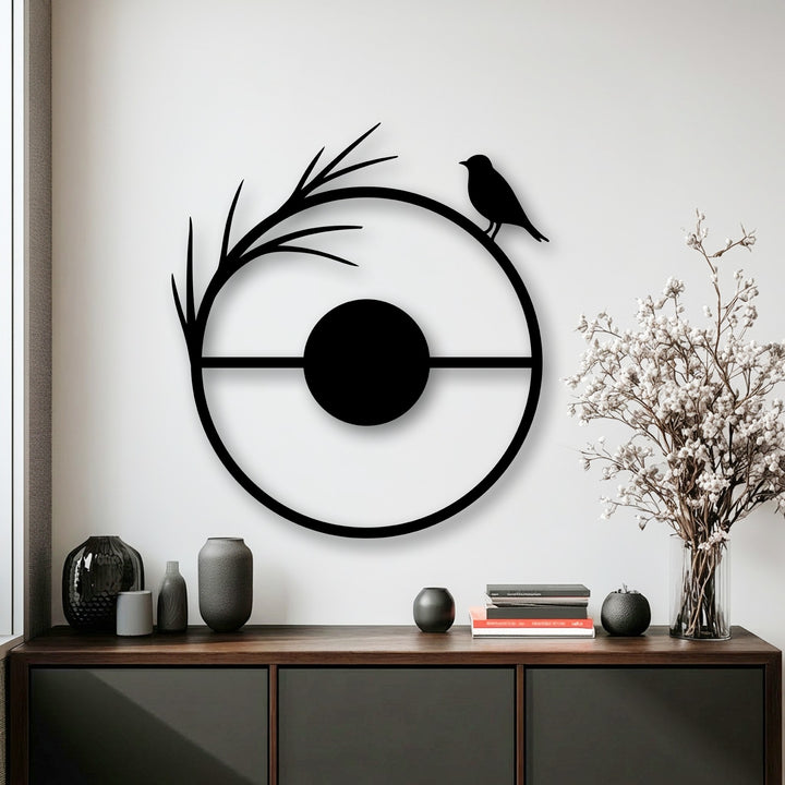 The central subject, a minimalist black circular metal artwork, elegantly depicts a bird perched on a branch silhouette, a stunning metal artwork.