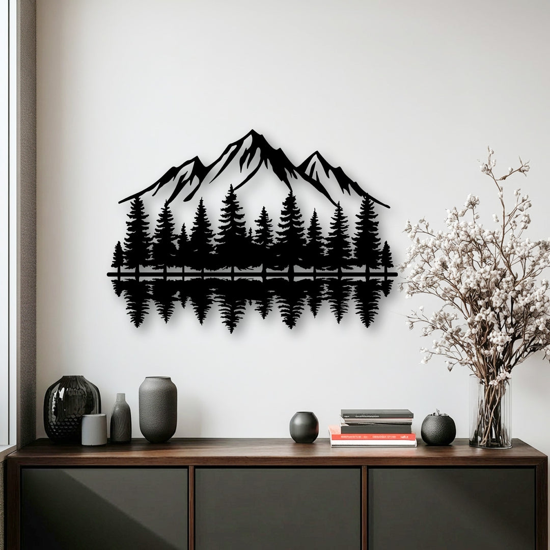 A striking black metal wall decor piece portrays a majestic mountain range and dense pine forest with a clear water reflection.