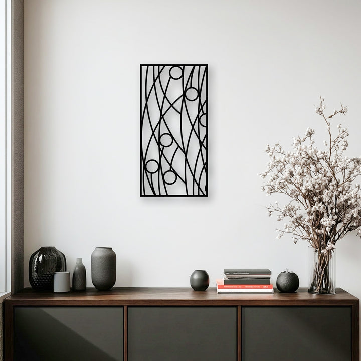 The desaturated color palette highlights the sleek black abstract metal artwork against a bright white wall, complemented by subdued decor.