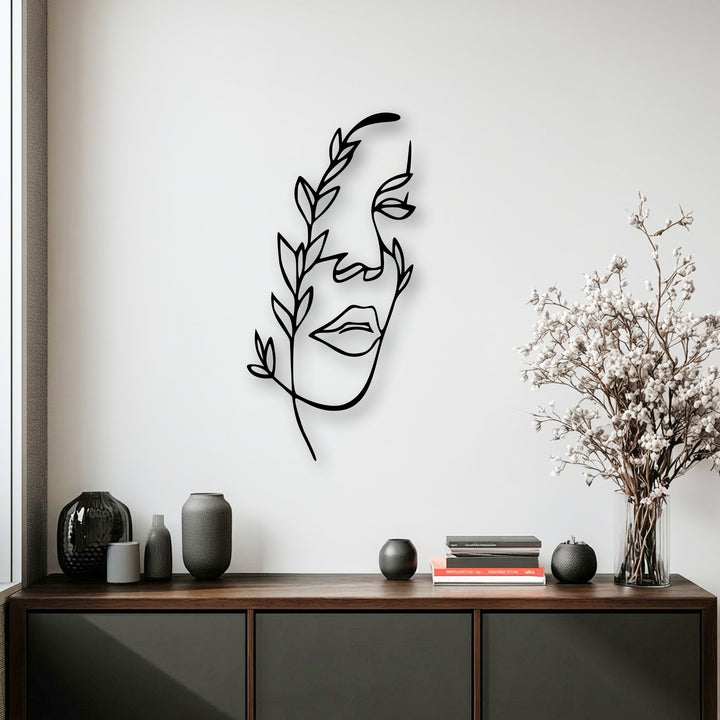 Dark vases and books on a credenza complement the botanical minimalist female line art metal wall decor.