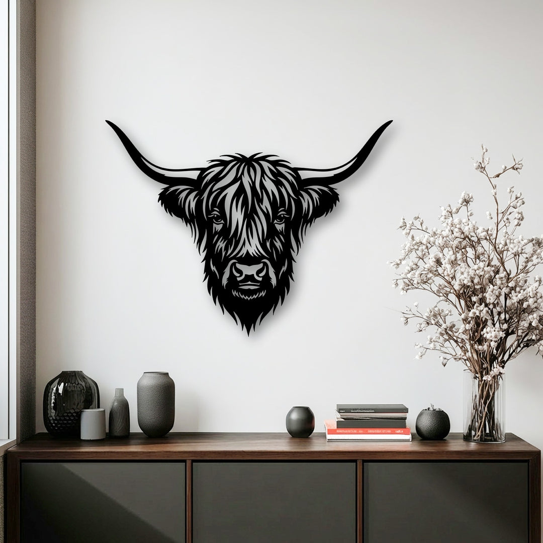 Various decorative objects and stacked books on a wooden credenza complement the striking Highland Bull Head metal art for wall.