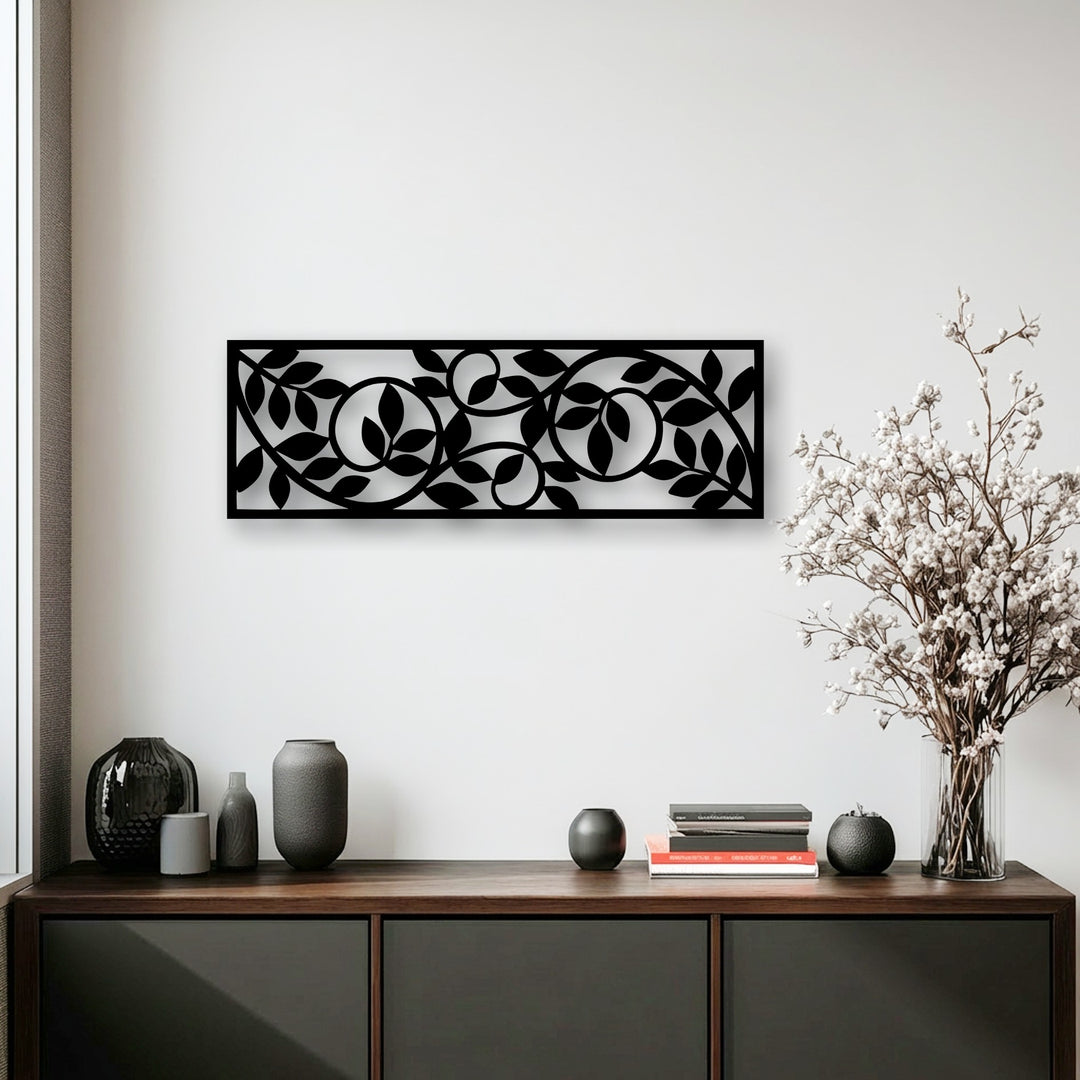 The striking black metal decoration wall art panel featuring a flowing botanical vine pattern is the central focal point above a rustic wooden console table.