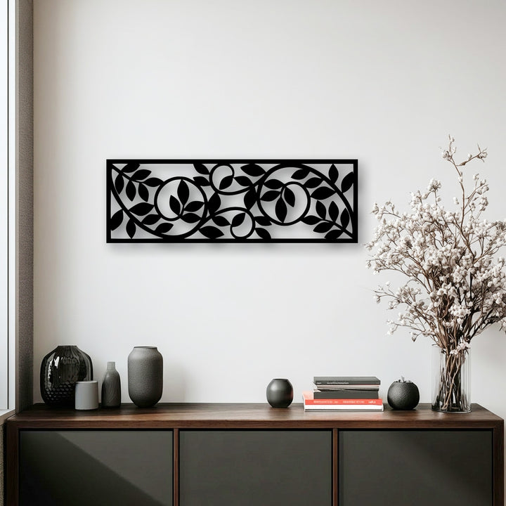 The striking black metal decoration wall art panel featuring a flowing botanical vine pattern is the central focal point above a rustic wooden console table.