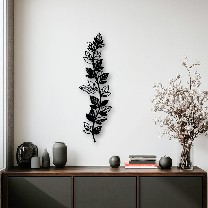 The cool color temperature in this modern setting highlights a stunning vertical botanical leaf branch metal artwork, accentuating the white wall.