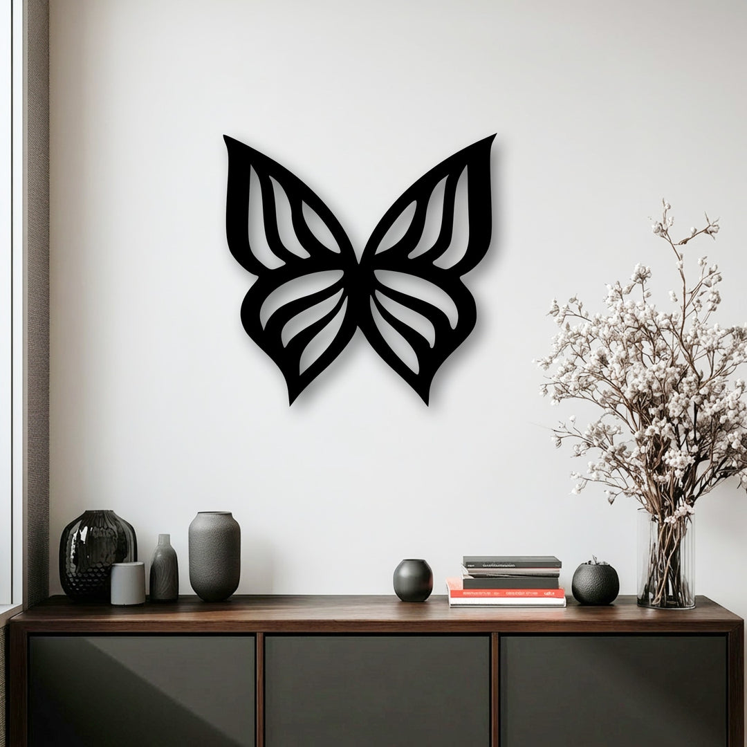 An elegant black butterfly silhouette, perfect as metal art for wall decor, features intricate cut-out wings on a white wall.