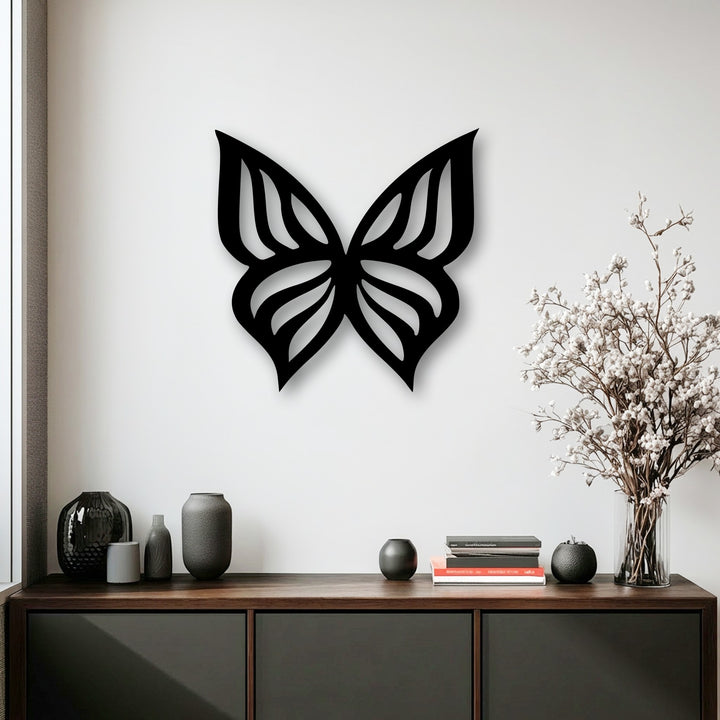 An elegant black butterfly silhouette, perfect as metal art for wall decor, features intricate cut-out wings on a white wall.