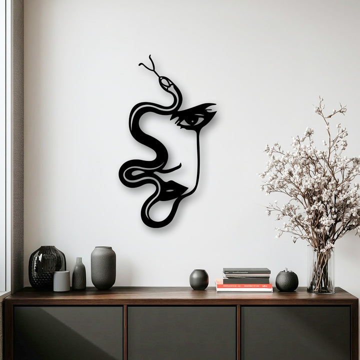 The negative space on the pristine white wall artfully defines the abstract woman and serpent silhouette in this unique metal wall art.