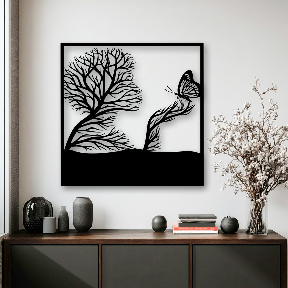 The realistic detail of intricate branches shaping a serene face and a delicate butterfly enhances this striking decorative metal art.