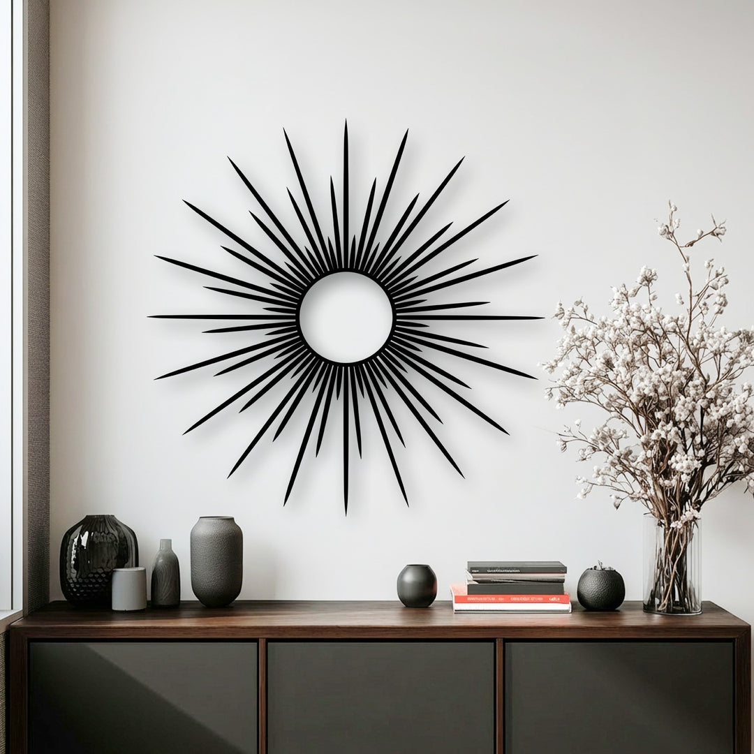 The bright white wall accentuates the sleek, abstract sunburst metal art for wall with its prominent circular core.