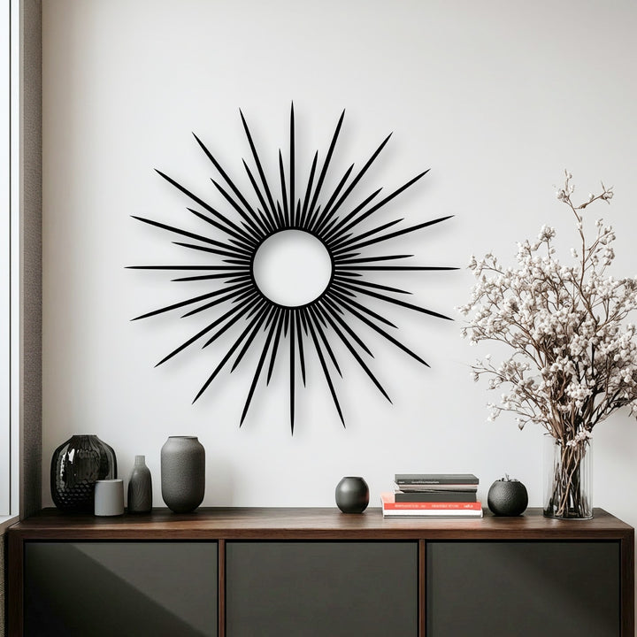 The bright white wall accentuates the sleek, abstract sunburst metal art for wall with its prominent circular core.