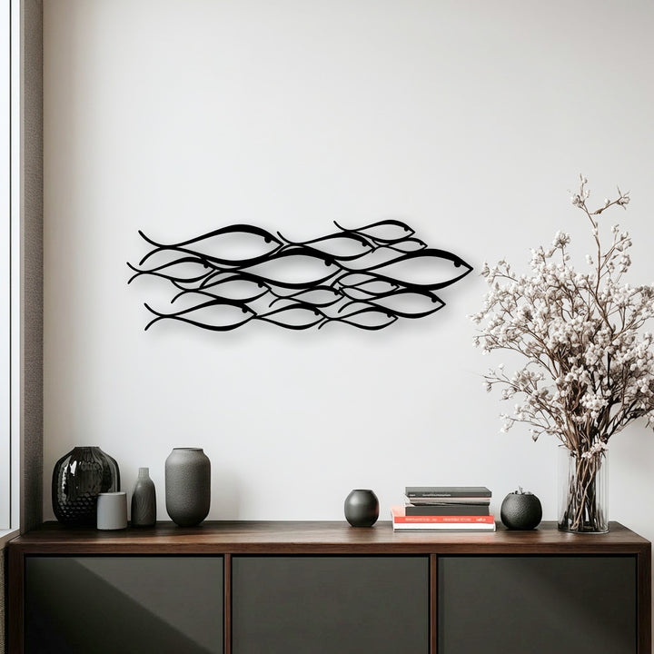 Abstract flowing black metal fish forms create striking decoration wall art, subtly detailing a school in motion.