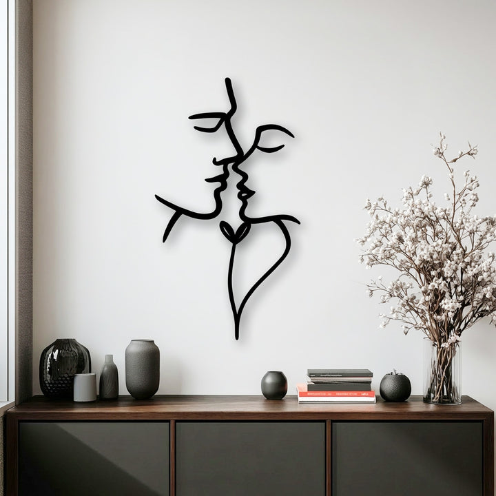 Smooth matte finish of the abstract face metal art for wall, accompanied by textured ceramic vases and dried floral elements.