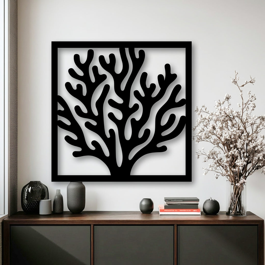 The tranquil mood of a sophisticated coastal space is enhanced by a framed black coral decorative metal art piece, complementing dark vases and white flowers.