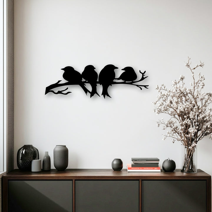 The matte black finish of the decorative metal art depicting birds on a branch contrasts with the glossy and textured vases below.