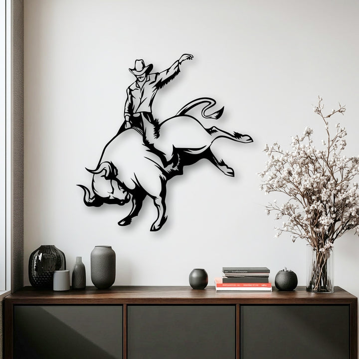 The stark transition from the pristine white wall to the deep black dynamic silhouette of a cowboy bull riding unique metal wall art.