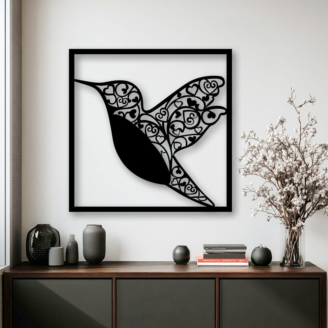 With low color saturation, this metal artwork of a black hummingbird with heart details stands out on a white wall with desaturated decor.