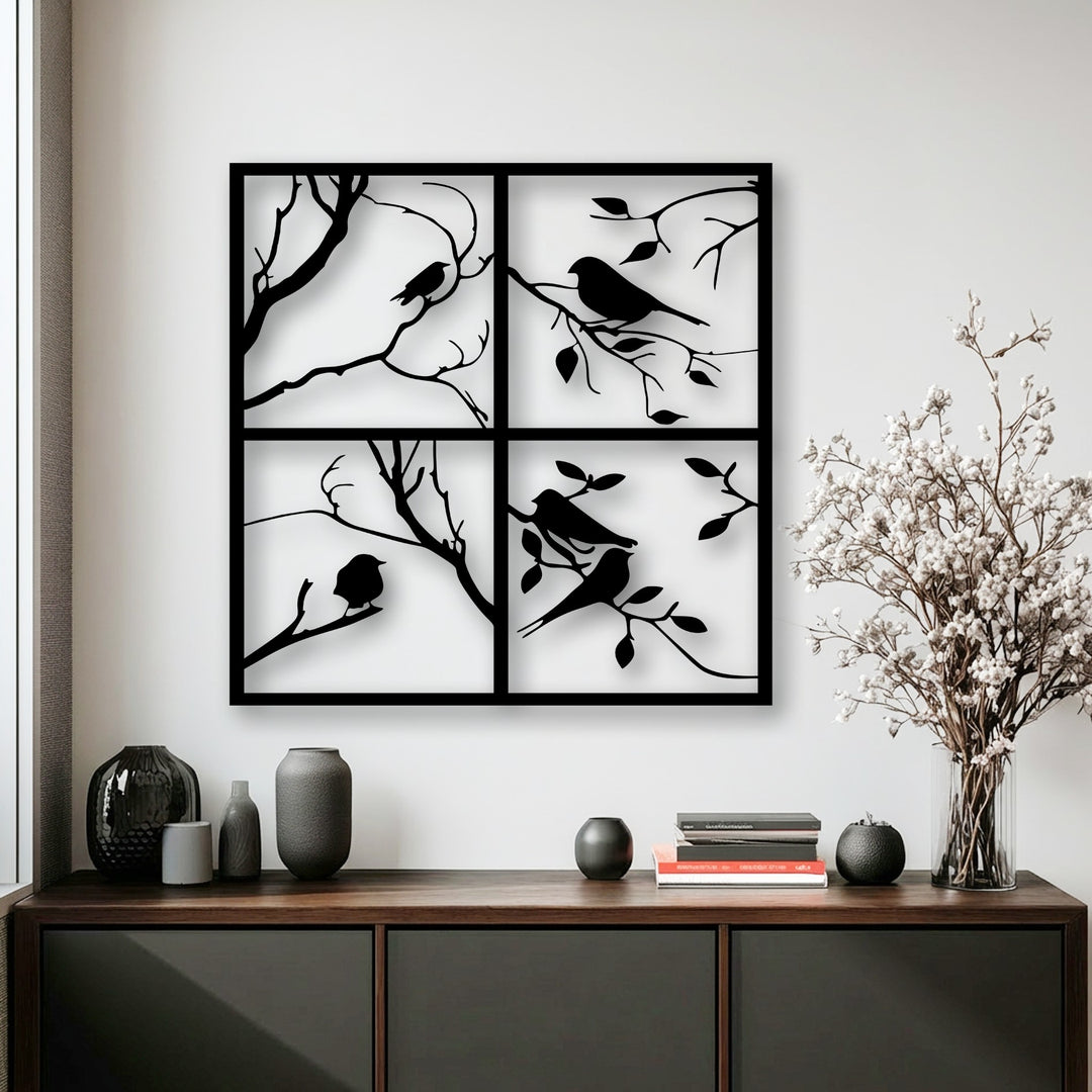 Negative space emphasizes the four panel bird silhouette metal art for wall, with dark branches and birds contrasting the bright background.