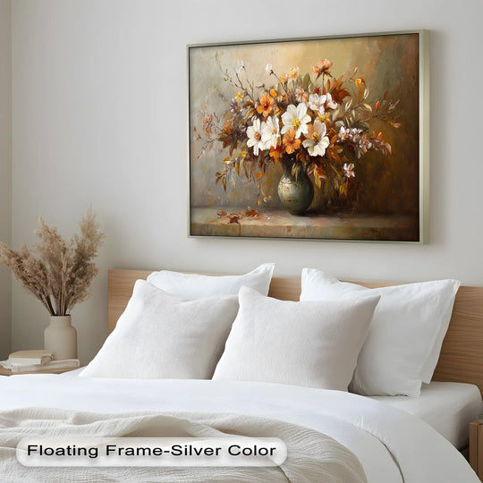 Framed old style vintage flowers dominate the scene as striking oil painting art prints, showcasing a classic floral arrangement with a silver floating frame above a bed.