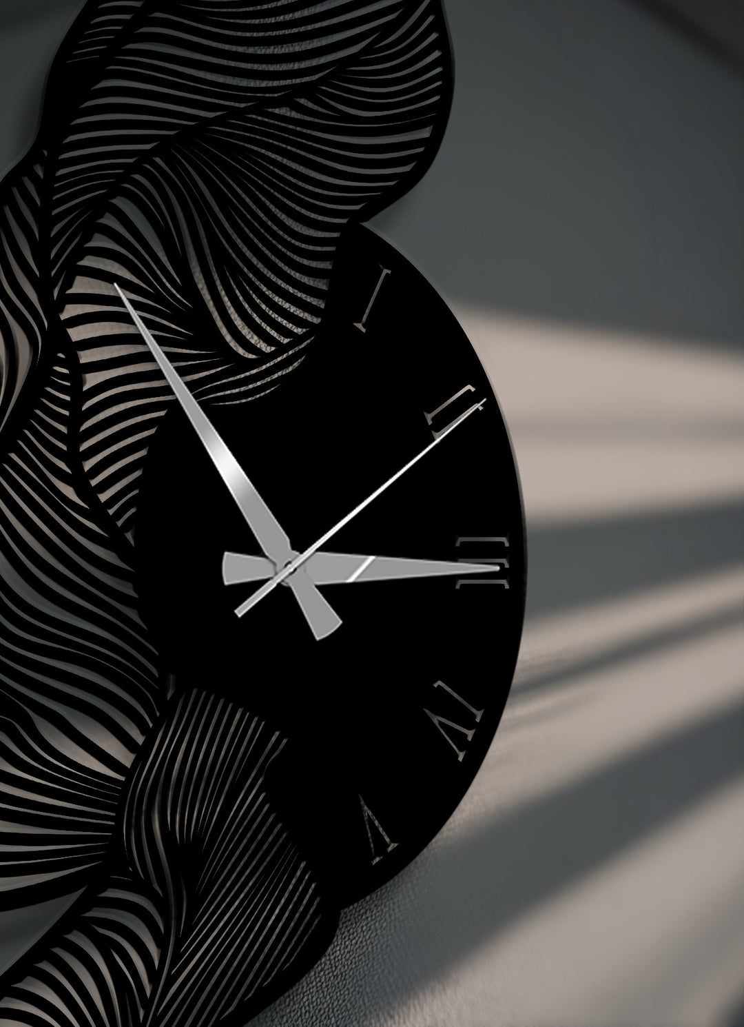 Gleaming silver hands contrast against the striking black face of a decorative metal art wall clock, featuring abstract wavy patterns and crisp Roman numerals.
