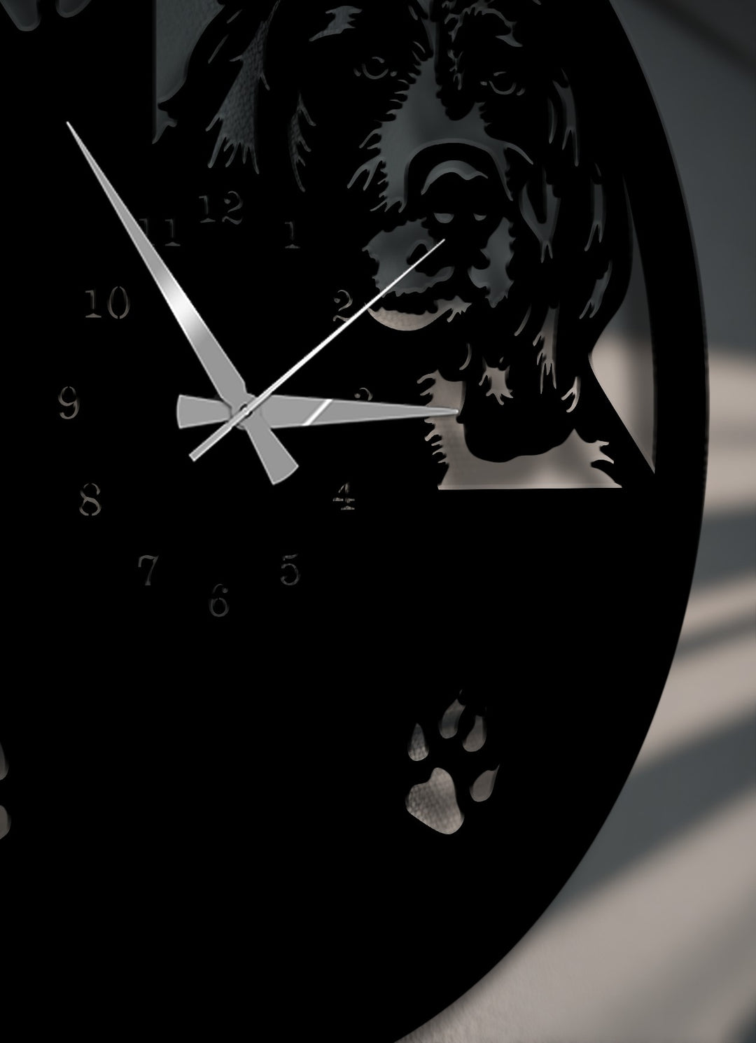 The deeply desaturated decorative metal art wall clock displays a striking black dog silhouette and paw print design with silver hands.