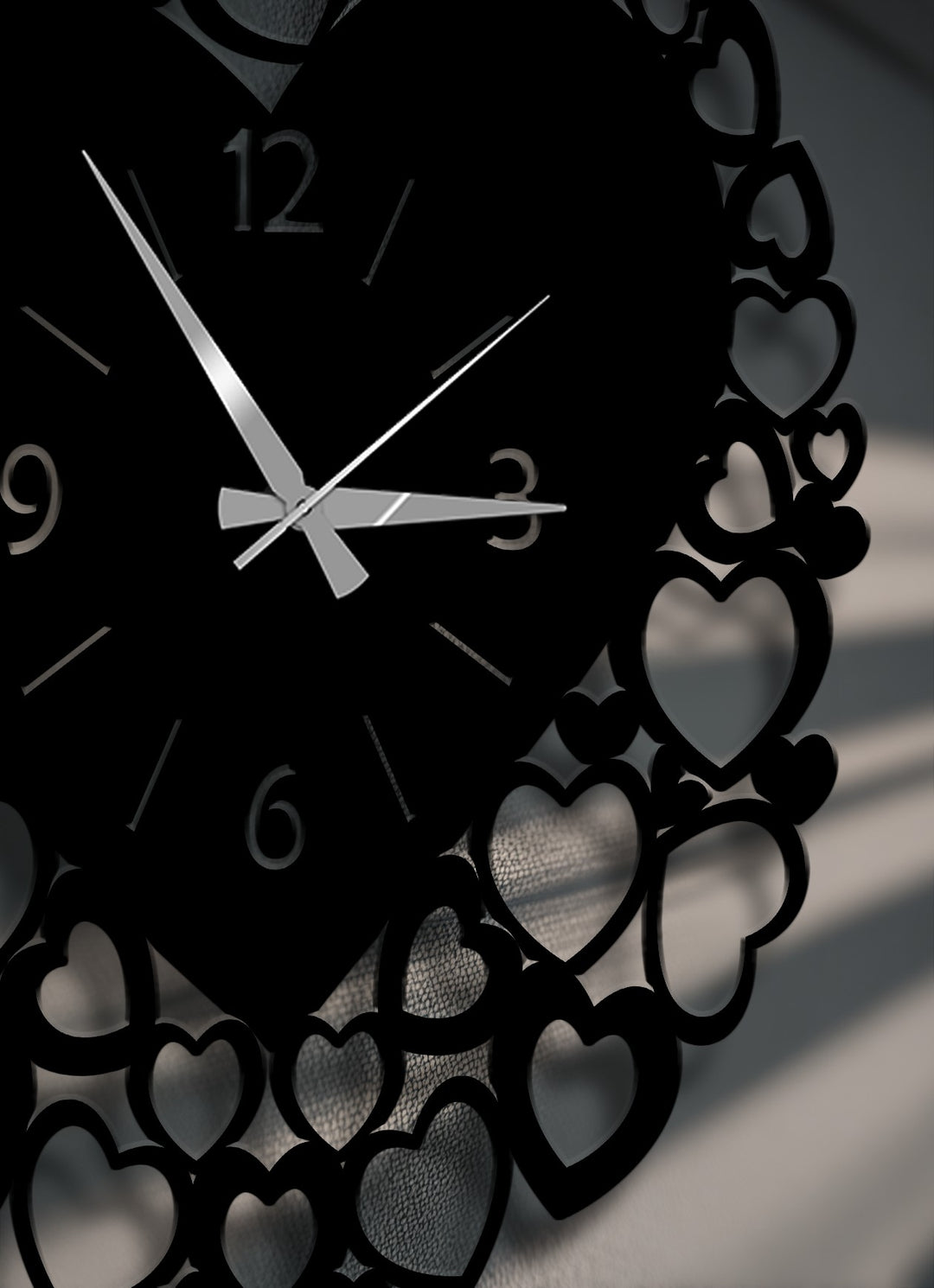 The gleaming white hands of a black heart-frame metal artwork wall clock are the focal point, with numbers 12, 3, 6, and 9 visible.